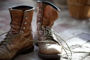 Distressed work boots sitting unlaced on brick floor